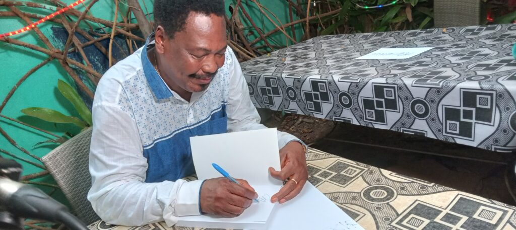Justin Morel Junior signant son nouveau livre "En direct avec les artistes du peuple de Guinée"